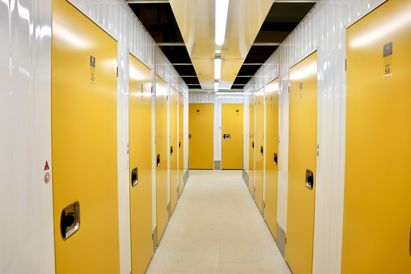 Indoor storage corridor lined with bright yellow unit doors, viewed toward the far end.