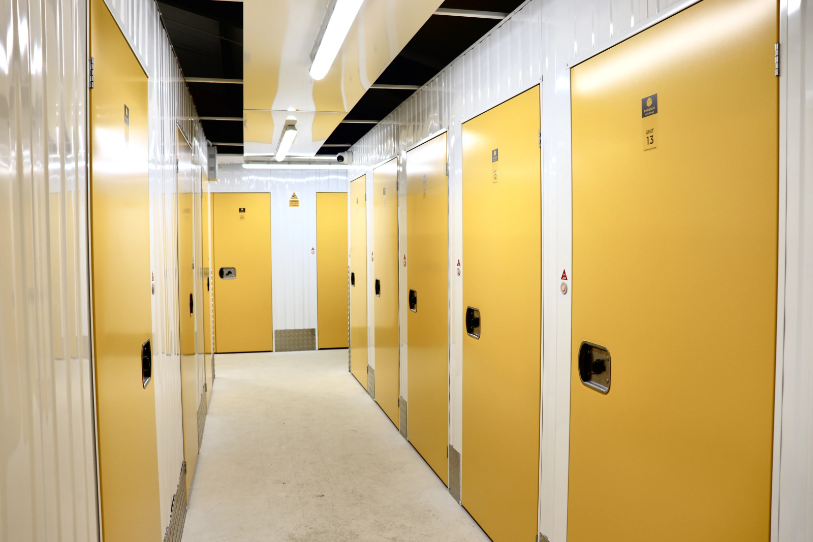 Indoor storage corridor with rows of bright yellow unit doors.